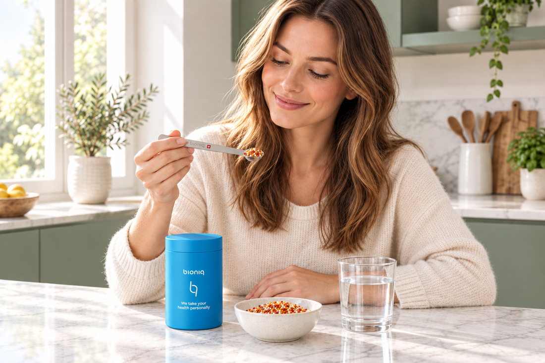 Donna in una cucina luminosa con il barattolo azzurro Bioniq con marchio e il cucchiaio con i granuli